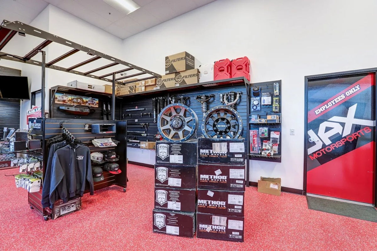 Jax Motorsports showroom merchandise area with wheels, JAX hoodies, and S&B Filters