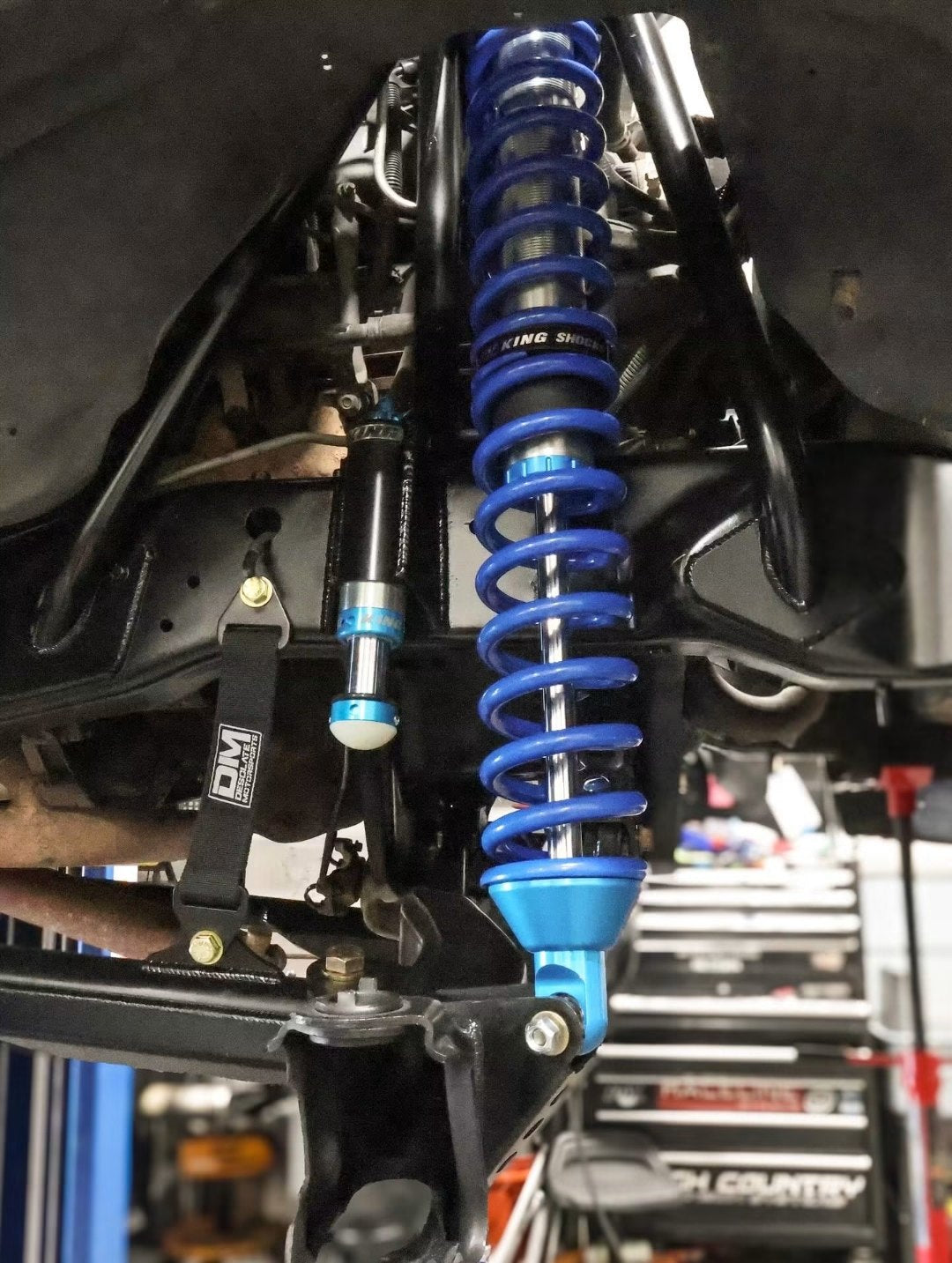 King Shocks coilover, hydraulic bump stop, and Desolate Motorsports limit strap installed on a lifted truck up on the rack in the Jax Motorsports shop