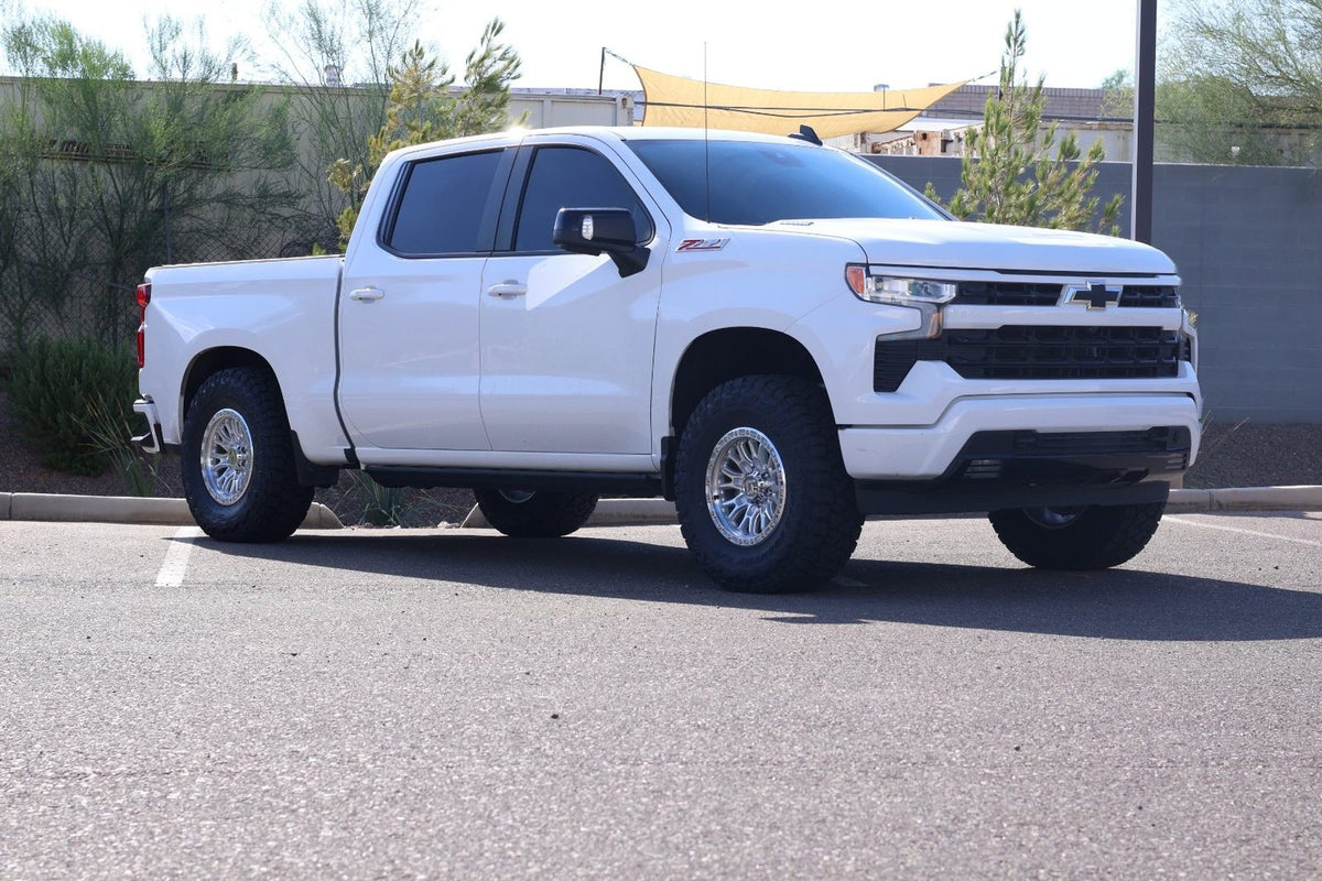After: lifted white Silverado Z71 front three-quarter with Hostile wheels
