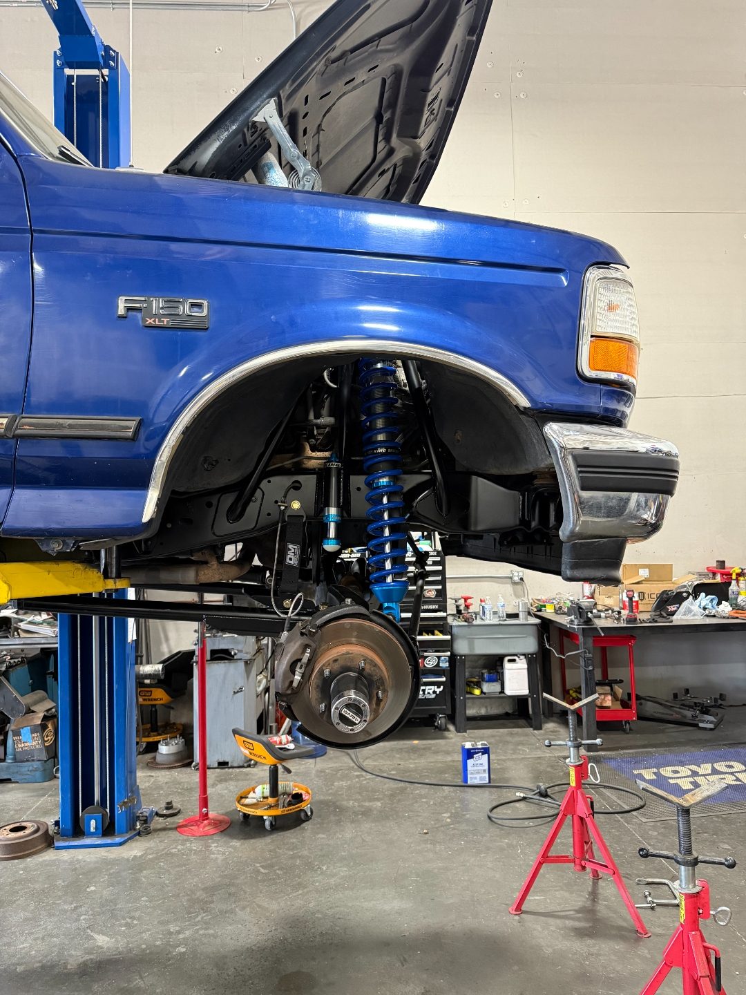 Wide side view of the front long-travel suspension with King shocks, Warn hub, and limit strap