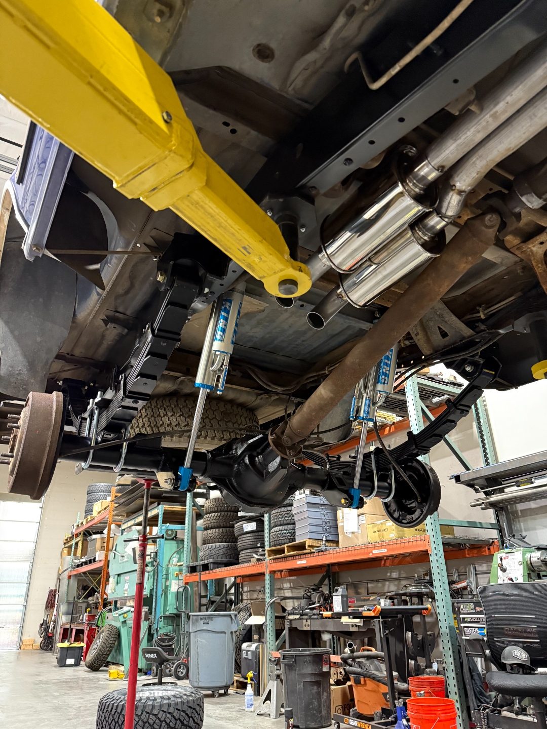 Undercarriage view of the rear axle with King bypass shocks, Deaver leaf spring pack, and dual stainless exhaust
